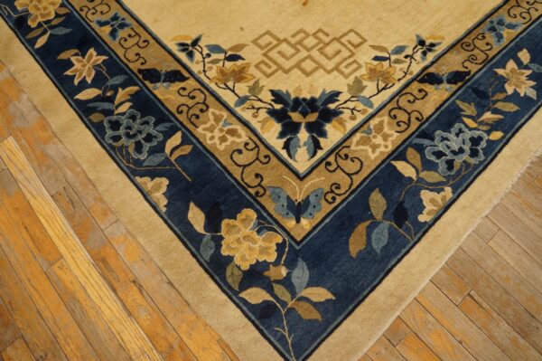 Beige field rug with elaborate blue and gold floral borders, visible on distressed wooden flooring.