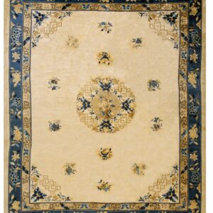 Ivory rug with wide navy blue floral borders framing a central gold and blue medallion design.