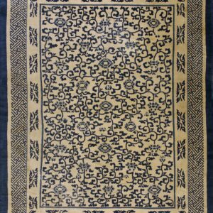 Beige rug with navy blue central scrolling floral pattern and dense geometric key borders.