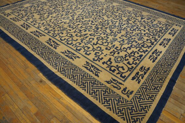 Blue floral pattern covers a beige rug with a wide geometric border, displayed on wooden floors.