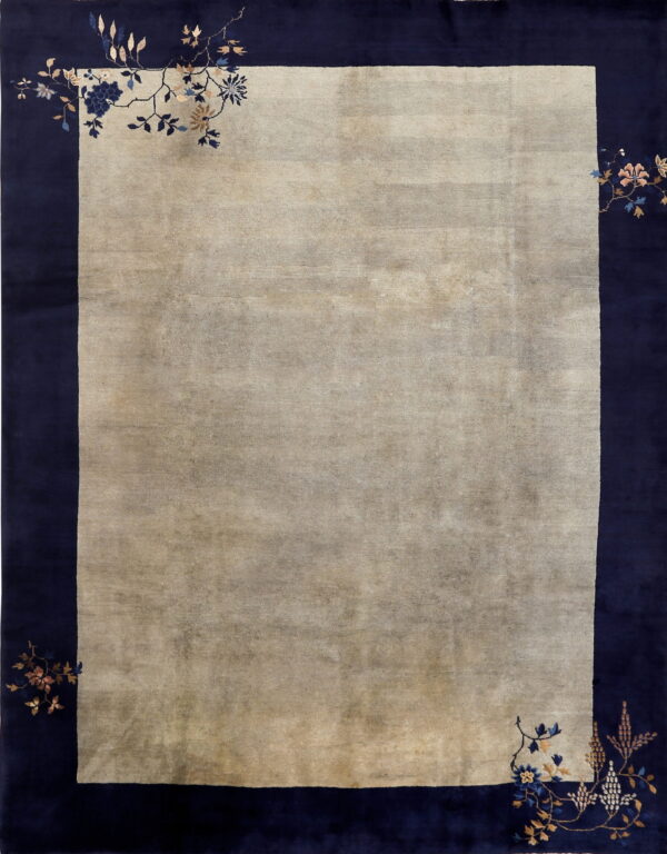 Muted beige rug with a wide navy blue border and delicate floral vine motifs in the corners.