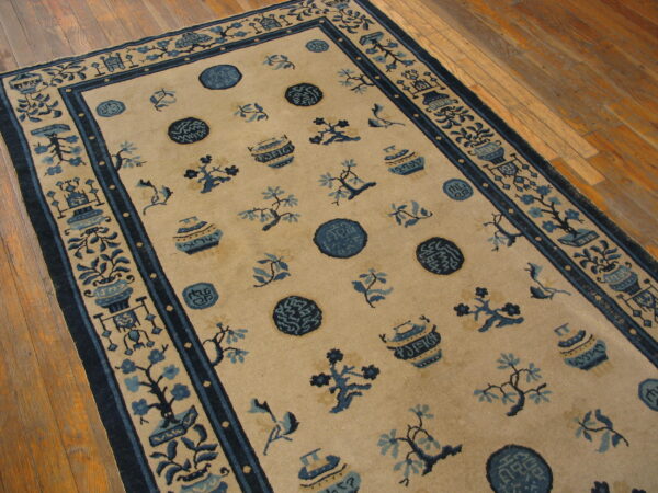 Beige rug featuring scattered blue floral, vase, and medallion patterns on a glossy wood floor.