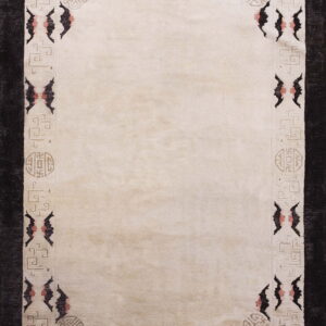 Light beige rug with a dark geometric border pattern and stylized bat shapes in black and pink.