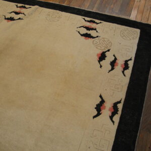 Tan rug featuring a black border, light fretwork, and black and pink bat motifs on wood planks.