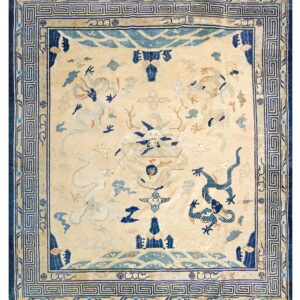 A square rug with a pale yellow field, navy and light blue dragons, and a geometric meander border.