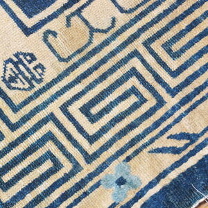 Indigo blue and tan rug with a tight meander pattern and small decorative symbols.
