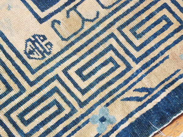 Indigo blue and tan rug with a tight meander pattern and small decorative symbols.