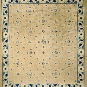 Light tan rug displaying a scattered blue floral pattern and a detailed indigo and cream scrolling vine border.