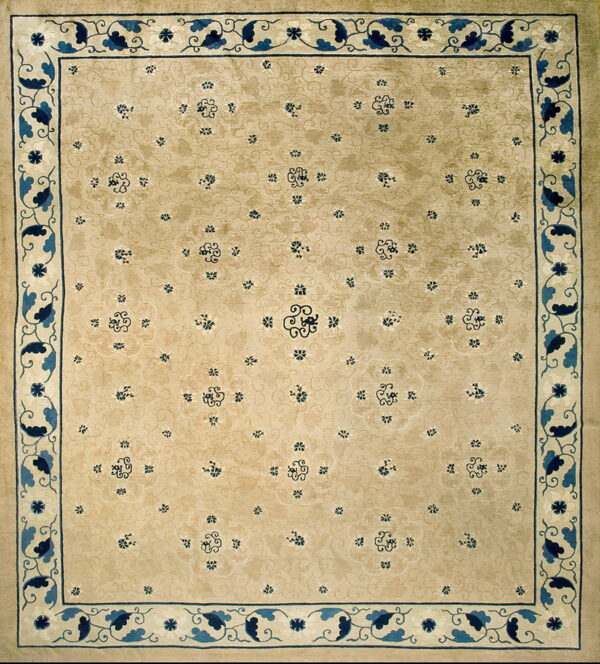 Light tan rug displaying a scattered blue floral pattern and a detailed indigo and cream scrolling vine border.