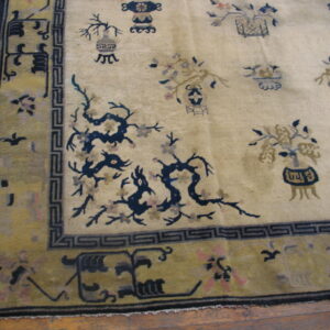 Cream rug with scattered blue and taupe vase motifs and dragons, framed by an olive green border on wood planks.