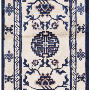 Cream rug featuring navy blue floral vines, a geometric medallion, and angular tan and blue double borders.