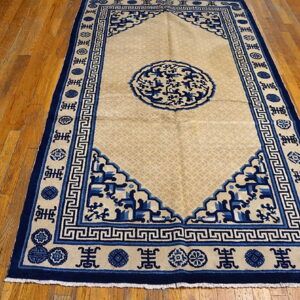 Low-pile rug in tan and deep blue featuring geometric and medallion designs on glossy wood flooring.