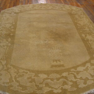 Rounded rectangular tan rug with a sculpted border featuring dragons and clouds over wood planks.