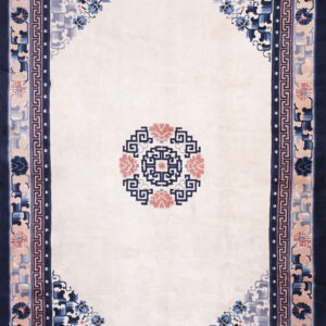 Rectangular cream rug with a navy, dusty rose, and blue floral border and a central geometric medallion.