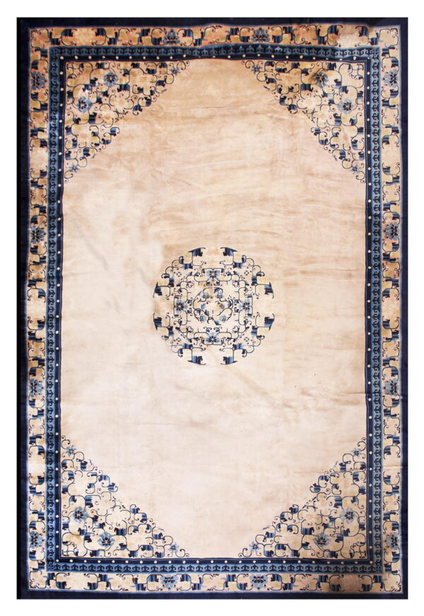 A light beige rug with a blue floral medallion and corner spandrels, framed by a wide navy border.