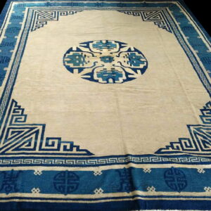 Rectangular cream and indigo rug featuring a dense geometric border and large central circular medallion design.