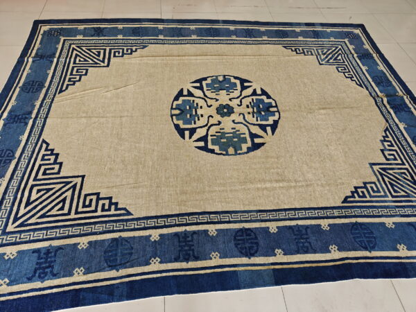 Antique chinese - peking chinese knotted rug 6 A tan and dark blue rug featuring a geometric border and round central medallion, displayed on white tile.