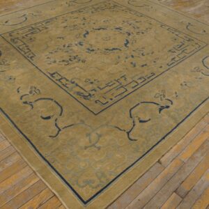 Gold and blue patterned rug with low pile rests on light brown, distressed wood flooring.