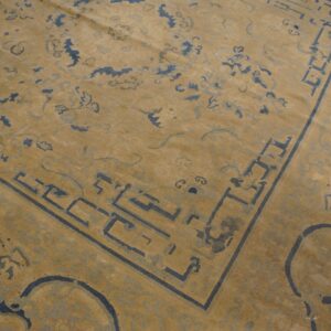 Low-pile rug detail showing a honey beige background with slate blue geometric and abstract cloud designs.