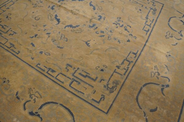 Low-pile rug detail showing a honey beige background with slate blue geometric and abstract cloud designs.
