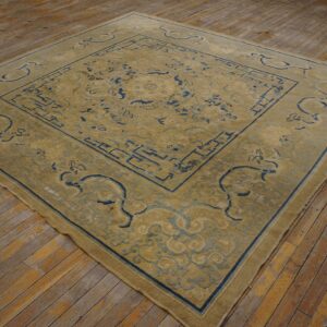 Gold rug featuring a complex blue border and central design on worn wood flooring.