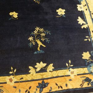 High-pile navy rug featuring a yellow bird and tree motif with wide orange and gold floral borders.