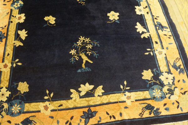 High-pile navy rug featuring a yellow bird and tree motif with wide orange and gold floral borders.