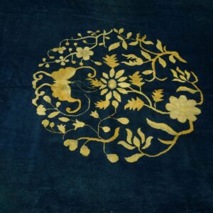 Deep blue rug with a central golden yellow medallion featuring flowing floral motifs.