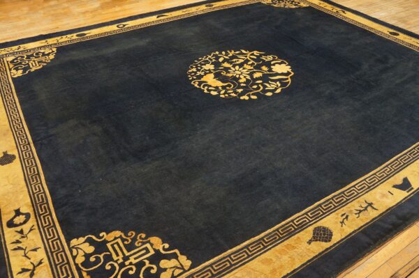 Navy rug with a gold border and central floral medallion displayed on light wooden floorboards.