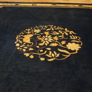 Black high-pile rug with a bright yellow floral medallion and decorative key border on wood floor.