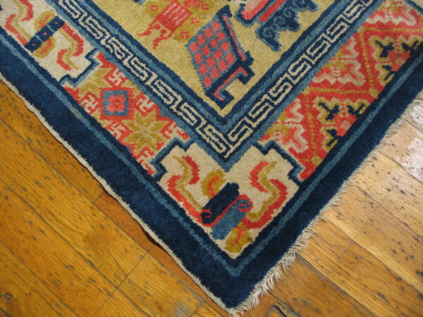 Geometric rug in navy, coral, and yellow with greek key pattern, laid on glossy wood planks.