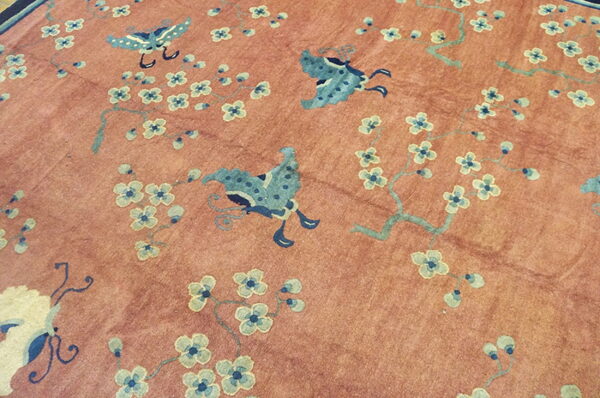 Pink and salmon-toned rug detailed with stylized blue butterflies and pale blue blossoms.