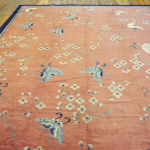 Pink rug with light blue butterflies and white flowers, dark blue border, placed on wood floor.