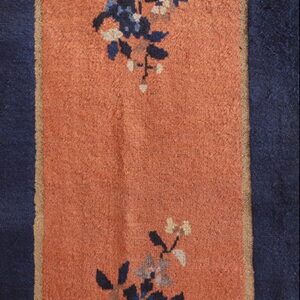 Terracotta runner rug with a navy border and blue floral motifs separated by a tan line.