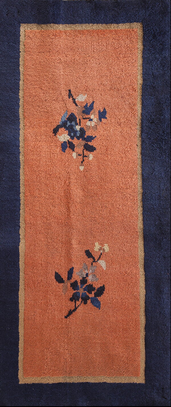 Terracotta runner rug with a navy border and blue floral motifs separated by a tan line.