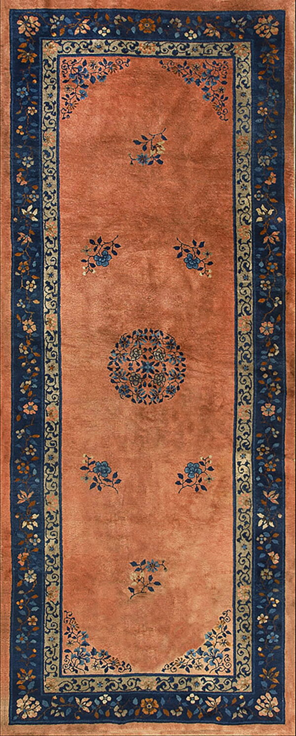 Long runner rug with a soft orange field, a central blue medallion, and detailed navy floral borders.