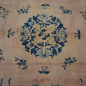 Textured rug featuring a dusty pink field and an intricate blue and yellow floral medallion design.