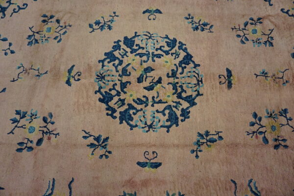 Textured rug featuring a dusty pink field and an intricate blue and yellow floral medallion design.