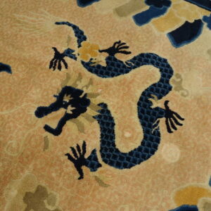 High-pile rug featuring a navy dragon and yellow accents on a peachy orange field near wood flooring.