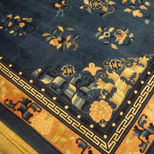 Deep blue rug with scattered gold and apricot floral patterns and a patterned border on wood floors.