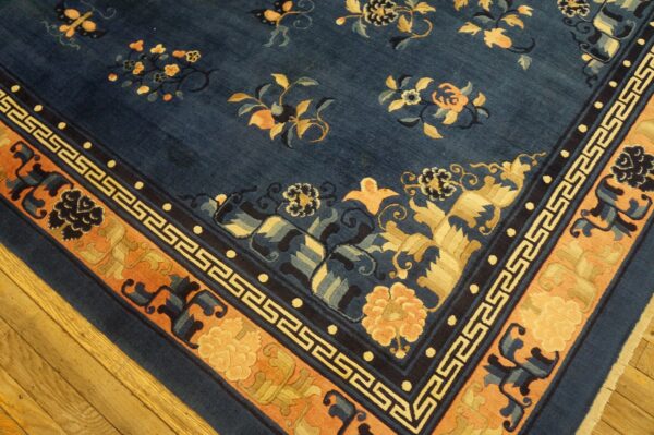 Deep blue rug with scattered gold and apricot floral patterns and a patterned border on wood floors.