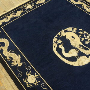 Low-pile navy rug with tan dragon borders and a round floral and bird medallion on hardwood floors.