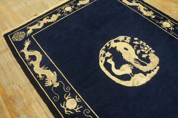 Low-pile navy rug with tan dragon borders and a round floral and bird medallion on hardwood floors.