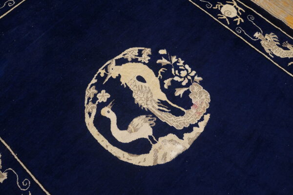 Dark blue rug detail showing a beige medallion with two stylized birds and a patterned border.