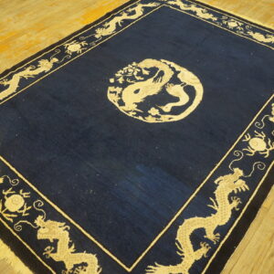Navy blue and light beige dragon rug on worn, wide plank wooden flooring.