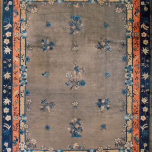 Gray field rug accented by blue floral sprays and a wide, detailed border of coral and navy.