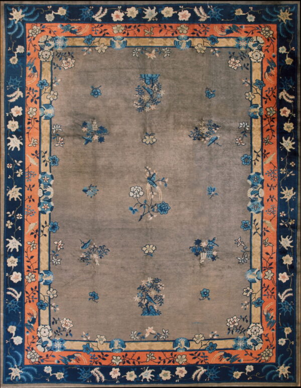 Gray field rug accented by blue floral sprays and a wide, detailed border of coral and navy.