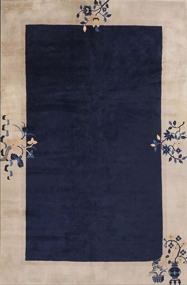 Rectangular rug with a deep navy center and a wide beige border featuring stylized blue and cream floral designs.