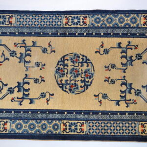 A tan rug runner features navy blue abstract vines and a central medallion, framed by a thick geometric border.