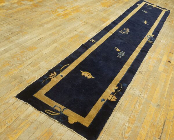 Navy blue chinese hallway runner with tan border on light hardwood flooring.